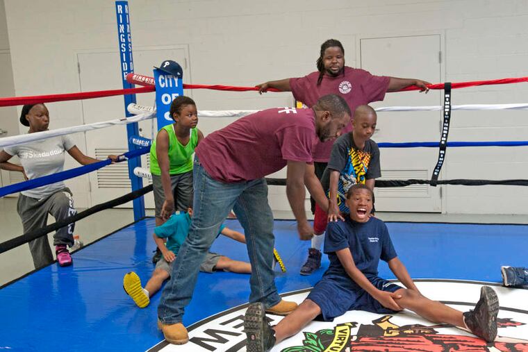 Boxing instructor Clement Bethea leans over to help Treshon Dumas, 13, with calisthenics at the North Camden Community Center. Camden hired Bethea to run the youth boxing program. Youths will not be allowed to spar but will learn discipline.