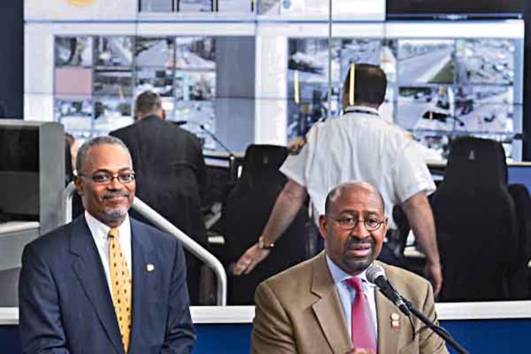 Chief of Staff and Deputy Mayor for Public Safety Everett Gillison (left) and Mayor Michael Nutter comment outside the glassed-in Real-Time Crime Center (rear) with all its video monitors inside the Delaware Valley Intelligence Center, following a tour of the new facility June 28, 2013. ( TOM GRALISH / Staff Photographer )