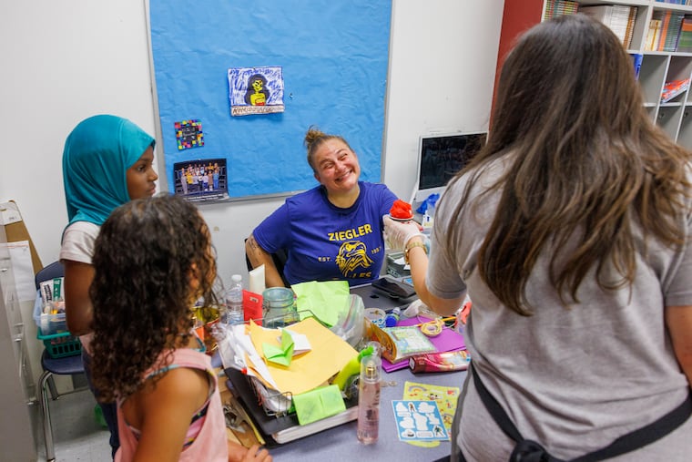 Third grade teacher Corrie Shields prepares to enjoy a cup of water ice being distributed to staff and students at Ziegler Elementary School in Philadelphia. Ziegler keeps attendance high the last week of school by packing days with incentives - a staff vs. students basketball game, field day, bubble parties, and other treats.