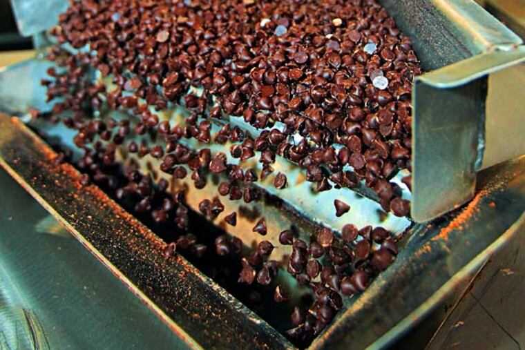 Thousands of chocolate chips fall off the converyor belt and into a hopper that will feed them into packing boxes that hold 50 pounds of the chocolate chips that Blommer makes. The nation's largest processor of chocolate beans (200,000 metric tons a year) has a huge factory in East Greenville. Demand for chocolate is up worldwide, but chocolate manufacturers are worried that demand may outstrip the supply of cocoa beans. Please refer to Leadership Agenda profile on company president Peter Blommer 04/10/2014 ( MICHAEL BRYANT / Staff Photographer )