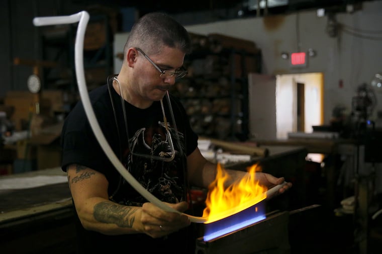 Tube bender Mike Gonzales heats up a glass tube with a ribbon burner to shape it into a curve at Spectrum Neon in Pennsauken, N.J., on Thursday, Aug. 23, 2018. Spectrum is one of the few remaining shops in the Philadelphia region that produces neon fixtures.
