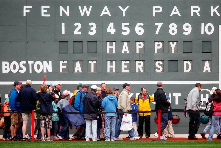 FILE - In this June 21, 2009 file photo, fans tour in front of the scoreboard in Fenway Park in Boston in celebration of Father's Day following a baseball game between the Atlanta Braves and the Boston Red Sox. The U.S. Census Bureau has released a new report showing more than 60% of the 121 million men in the U.S. are fathers. The data in the report released this week of June 15, 2019, comes from 2014 when the bureau for the first time asked both men and women about their fertility histories. The report says just under three-quarters of fathers are married. Almost 13% of dads are divorced and 8% have never been married. (AP Photo/Michael Dwyer)