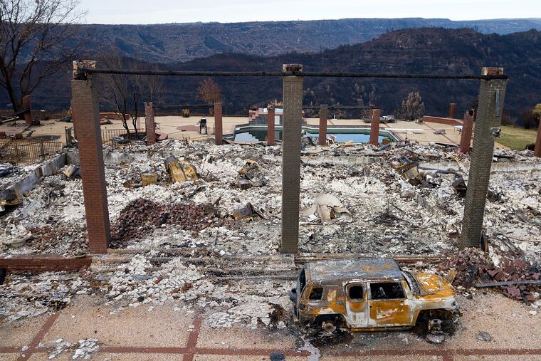 FILE - In this Dec. 3, 2018 file photo, a vehicle rests in front of a home leveled by the Camp Fire in Paradise, Calif. Authorities estimate it will cost at least $3 billion to clear debris of 19,000 homes destroyed by California wildfires last month. State and federal disaster relief officials said Tuesday, Dec. 11, 2018, that private contractors will most likely begin removing debris in January from Butte, Ventura and Los Angeles counties and costs are likely to surpass initial estimates. (AP Photo/Noah Berger, File)