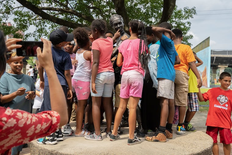 Young children run up to the statue portraying a young African American girl basketball player.