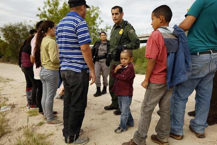 Ely Fernandez is questioned by border patrol agent Robert Rodriguez after being detained for crossing the border illegally with his son 5-year-old Bryan, center, on March 15, 2018 in McAllen, Texas.