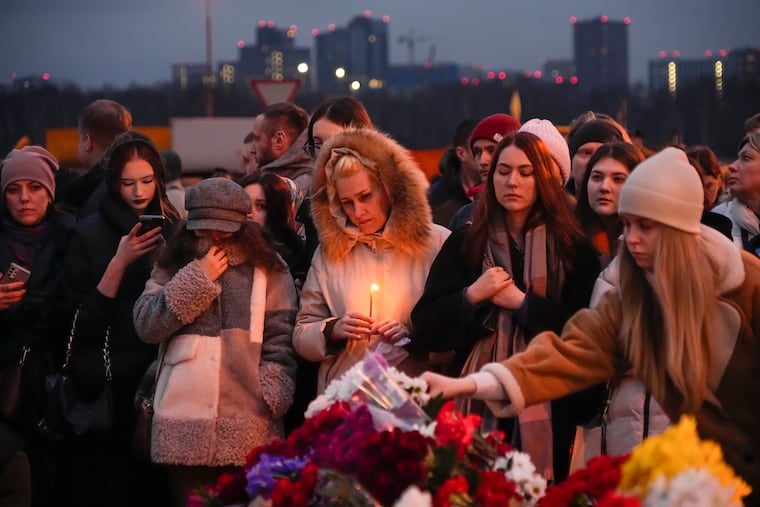 People lay flowers and light candles standing next to the Crocus City Hall on the western edge of Moscow on Saturday.