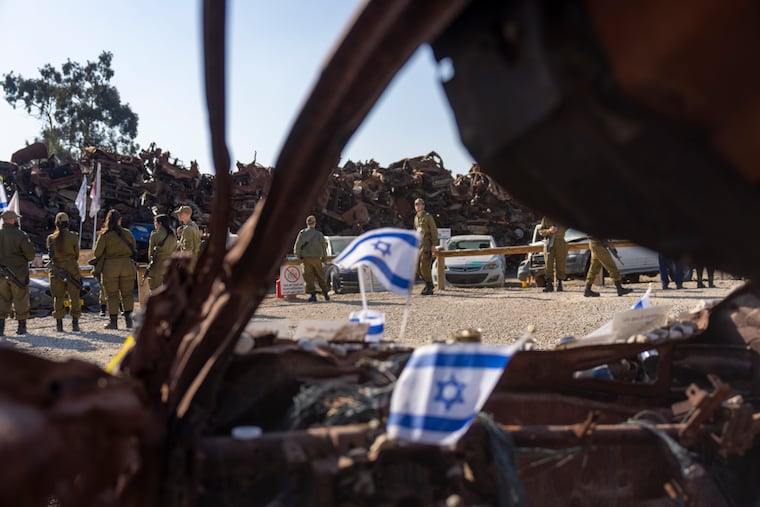 Israeli soldiers look at charred vehicles burned in the Oct. 7 , 2023, cross-border attacks by Hamas militants outside the town of Netivot, southern Israel, on Monday, Jan. 13, 2025.