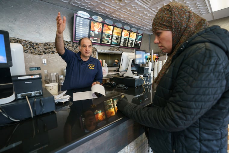 Shervin Manzari, owner of Cameron’s Seafood, talks with activist Jennifer Bennetch at his business, which is located in the area of a new proposed Business Improvement District on North Broad Street.