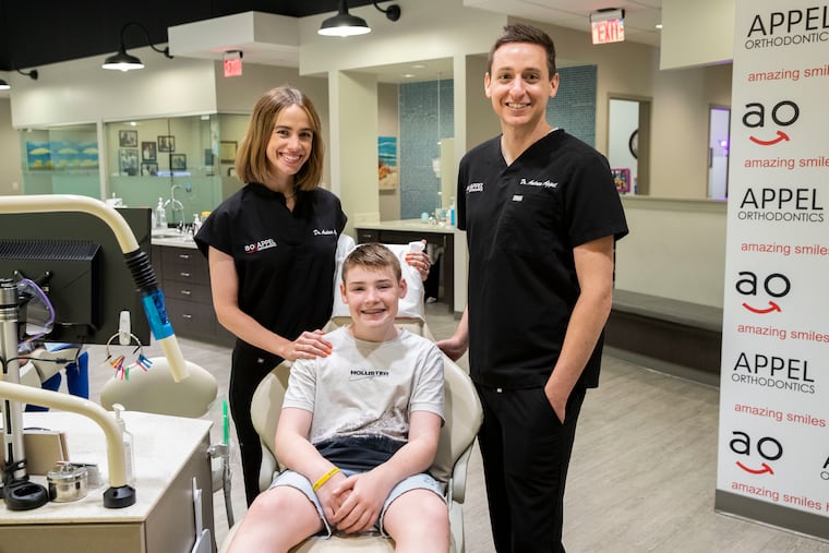 Andrea Appel, Jason Stock, 13, and Andrew Appel posed for a portrait at Appel Orthodontics in Philadelphia. Andrew Appel, of Appel Orthodontics, is offering free orthodontic care to one young cancer patient in remission per month, indefinitely. Jason Stock is the first patient.