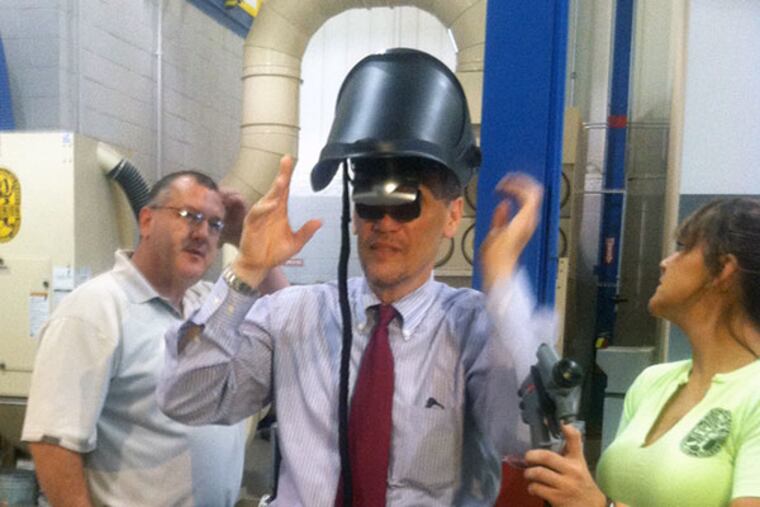 U.S. Labor Secretary Thomas Perez tries out a spray paint simulator at the Finishing Trades Institute in Northeast Philadelphia run by District 21 of International Union of Painters and Allied Trades and their contractor employers. He is assisted by Joseph Weiss, an apprentice coordinator, and Natalie Holzer, a second-year apprentice. (Jane M. Von Bergen/Staff)