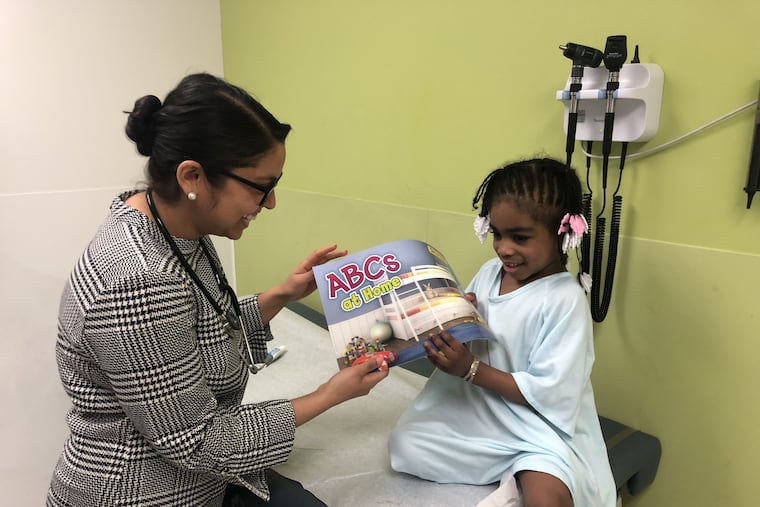 Hera Mahmood gives Aubrey Brown, 4, a book.