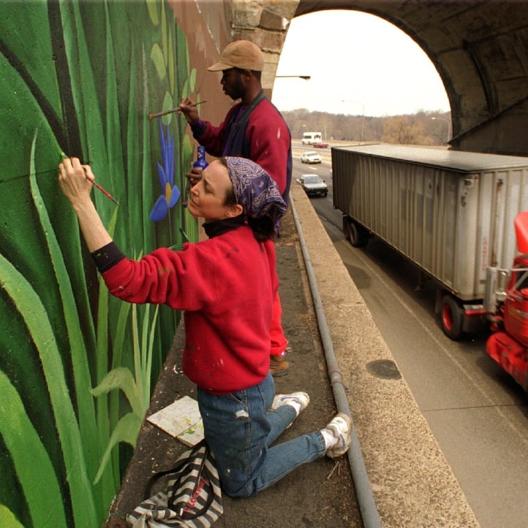 Jane Golden, artistic director of the Anti-Graffiti Network, works on a four-story mural with the help of Haisonn Shadding high above the Schuylkill Expressway near the zoo exit. Photo from March 25, 1994
