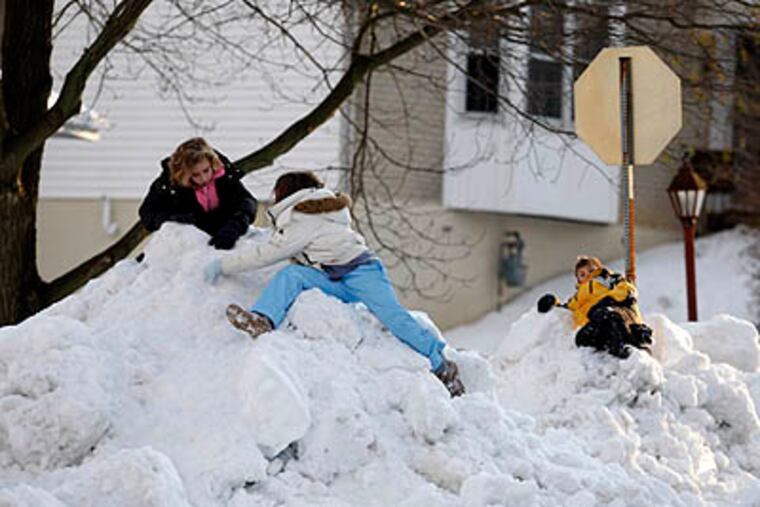 Rachel Mills and Shelby Moore, both 10, and Mitchel Mills, 9, Rachel's brother, took advantage of a snow day and street plowing to form giant snow mountains on Monday, in Claymont, Del. (Ron Cortes / Staff Photographer)