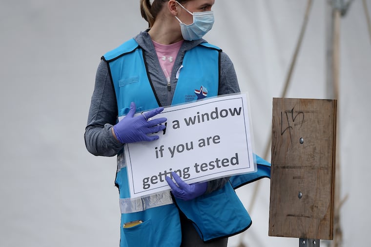 Philadelphia Medical Reserve Corps volunteer Lacee Collins, a medical student at Drexel University, directs cars at the city's coronavirus testing site next to Citizens Bank Park in South Philadelphia on Friday, March 20, 2020. The site is the first city-run drive-thru location, where people can be swabbed to determine if they have the coronavirus. At the time of opening, it was only for people with symptoms who are over 50 and health-care workers with symptoms.