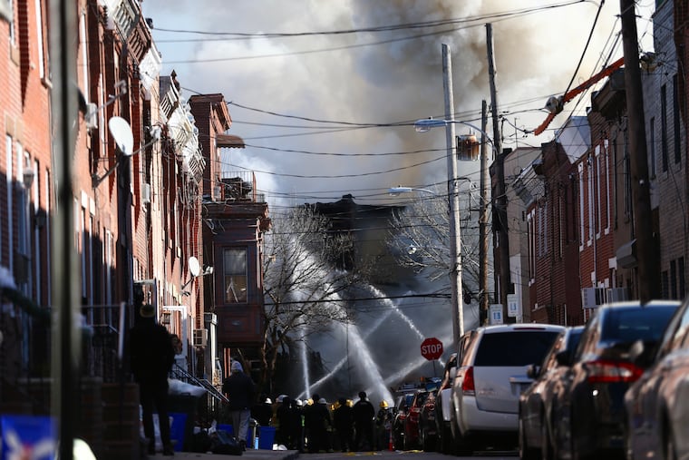 Firefighters battle a fire after an apparent explosion in the 1400 block of South 8th St. in Philadelphia on Thursday, Dec. 19, 2019.