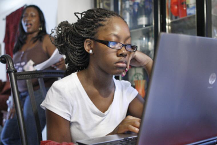 Naveda Walker, 14, does work for Agora Cyber Charter School on a home computer in Overbrook as mother Wanda watches. (Elizabeth Robertson / Staff Photographer)