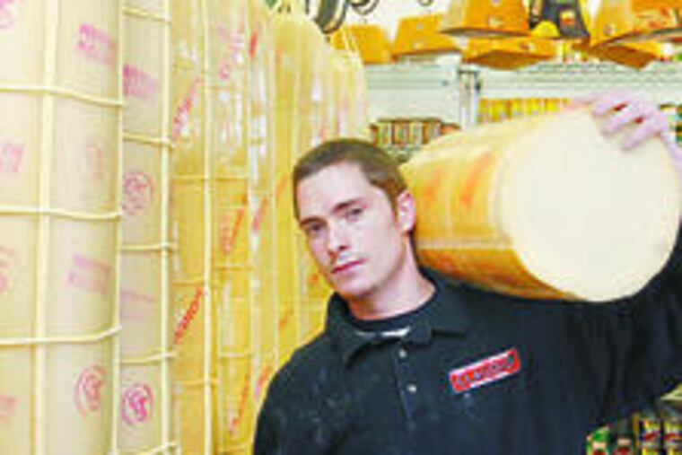 Salvatore Auriemma , the founder's grandson, hoists 60 lbs. of aged provolone at Claudio's.