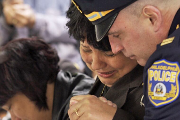 Pat Santiago, mother of Officer Isabel Nazario, is comforted by Philadelphia Police Capt. Jim Kelly as Santiago’s other daughter, Mimi Mohamad, makes a rubbing of the engraving of Nazario’s name from the memorial. (Jamie Rose / For MCT)