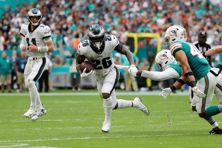 Eagles running back Miles Sanders runs with the football past Miami Dolphins defensive end Taco Charlton and defensive back Nik Needham on Dec. 1, 2019.