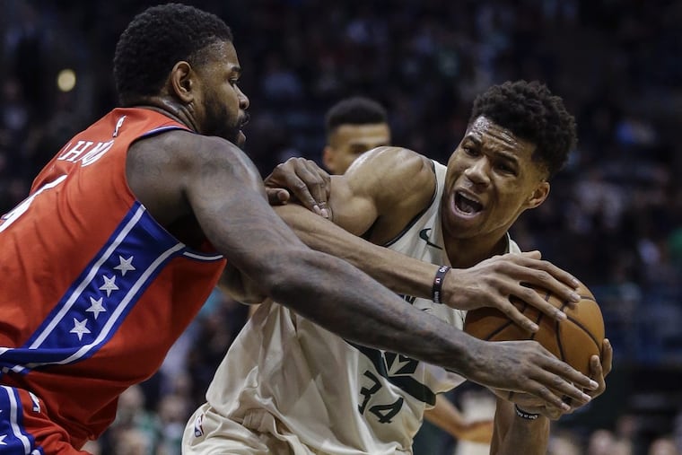Giannis Antetokounmpo of the Bucks is tied up by the 76ers’ Amir Johnson during the second half.