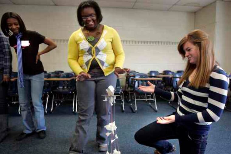 Volunteer Monise Moses (left), a civil engineering student at Widener, examines a model skyscraper built of drinking straws, plastic dough, and tape by Shaquanna Leak (center), 15, of Carver High in Philadelphia, and Keri Leonard, 17, of Upper Darby High.