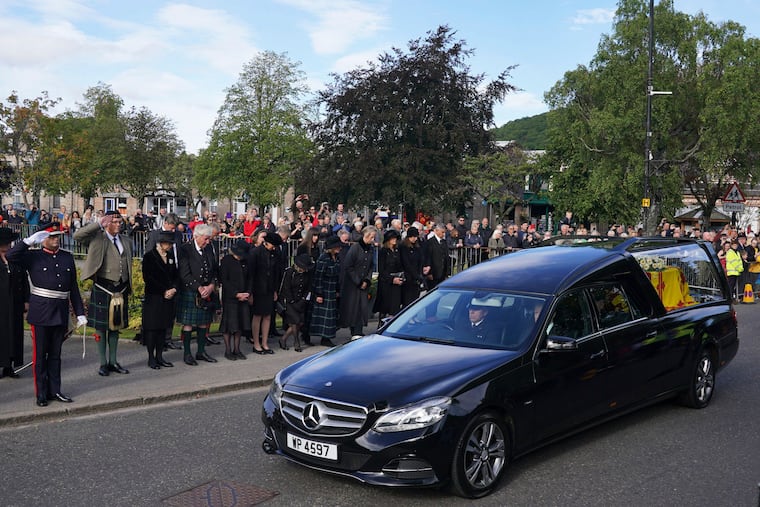 Members of the public line the streets in Ballater, Scotland, as the hearse carrying the coffin of Queen Elizabeth II passes through as it makes its journey to Edinburgh from Balmoral in Scotland, Sunday, Sept. 11, 2022.