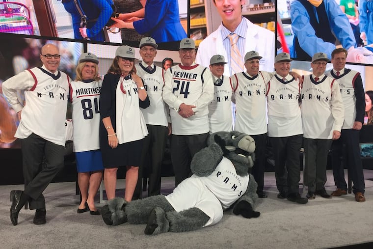 Thomas Jefferson University and Philadelphia University are set to formally combine their operations Saturday. Here Jefferson president and CEO, Stephen K. Klasko (L), and other executives show off new Jefferson basketball jerseys, with the Ram mascot lying in front.