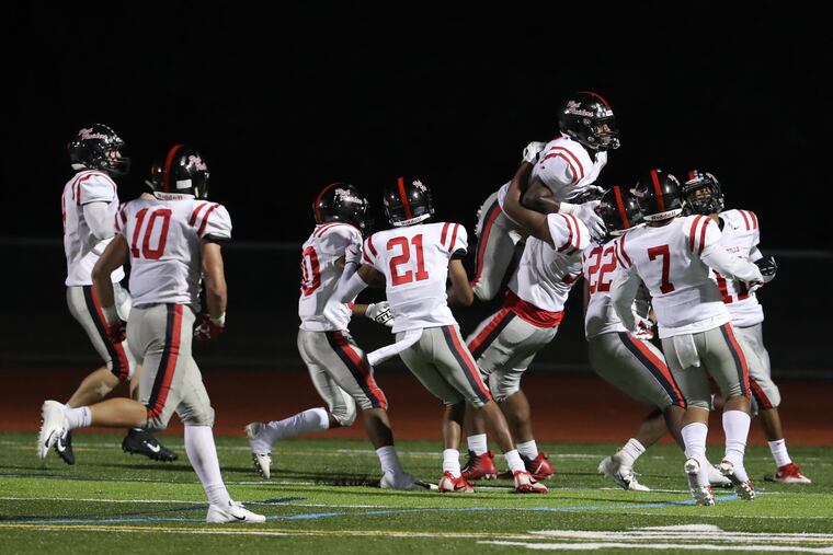 Dapree Bryant (center) of Coatesville is lifted up after intercepting a pass and returning it for a touchdown to seal a 34-21 victory over Unionville on Friday night.