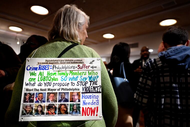 Mina Smith of Center City wears a placard as she mingled with mayoral candidates during a forum at the William Way LGBT Community Center in January. Whoever is elected mayor will shape Philadelphia for years to come.