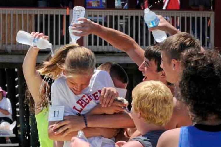 Teammates douse Emily Cavacini 11, of Shaler Township, PA with water bottles after she won the Girls Championship in the 90th annual National Marbles Tournament on the beach in Wildwood Thursday, June 20, 2013. ( TOM GRALISH / Staff Photographer )