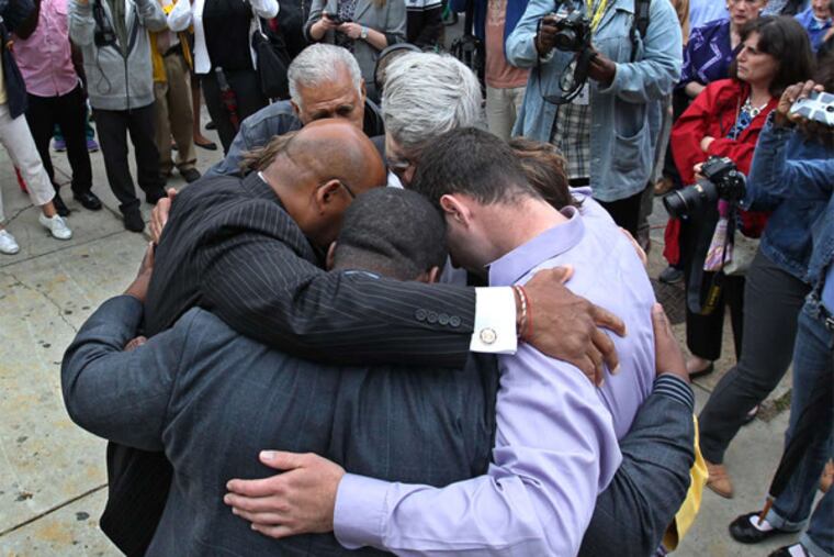 After planting a tree at the site of the deadly wall collapse onto the Salvation Army thrift store one year ago, Mayor Nutter and family members who lost a loved one gather in a prayer circle for a moment during a ceremony Thursday morning. The site will become a memorial park.