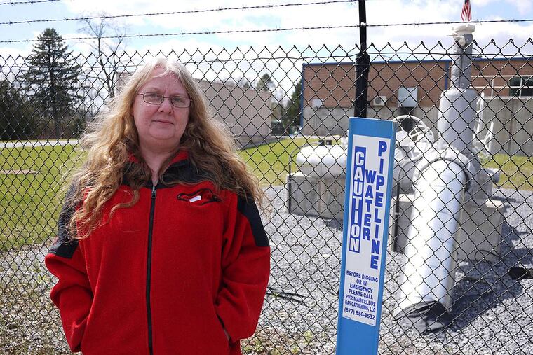 Gerlinde Trimble stands outside the fence of the Aqua America water pumping station near Jersey Shore, Pa., where she and her husband, Blake, once lived.