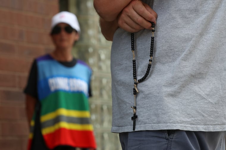 Antiabortion protester Mark Houck (foreground) holds a rosary as he stands opposite a patient escort outside of the Planned Parenthood in Center City.