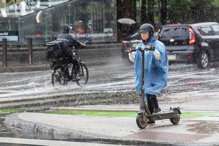 A woman rides her scooter during a rainstorm on July 21. Flooding rains are possible to start the workweek.