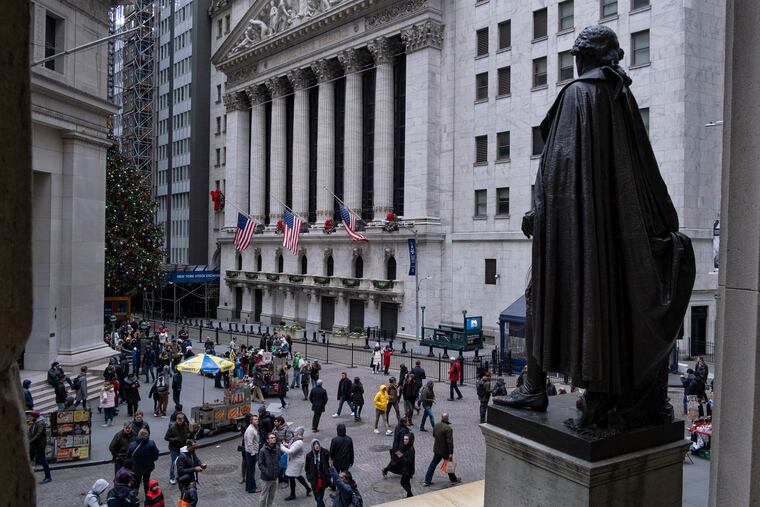 People stand near a statue of George Washington, adjacent to the New York Stock Exchange, background, Saturday, Dec. 22, 2018, at the closed Federal Hall National Memorial in New York.