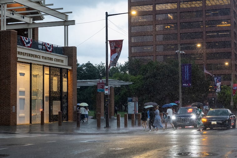 Pedestrians walk across Sixth and Market Street during a July 21 rain storm that bore some similarities to what didn't happen Tuesday night in Philly.
