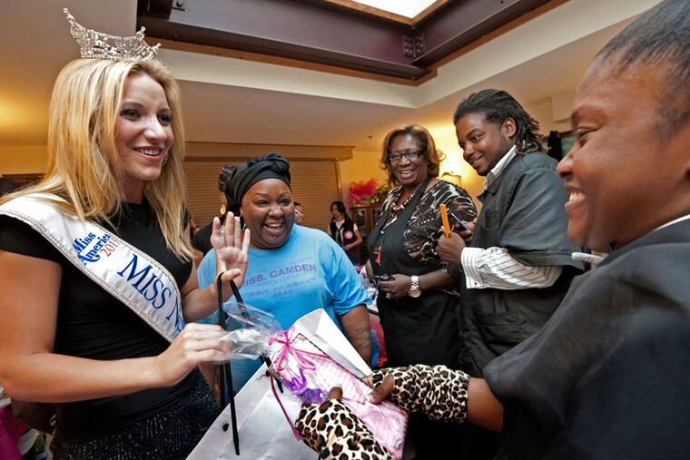 Miss New Jersey, Cara McCollum gives a gift to Esiyah Waheed, 14, right, in August 2013.