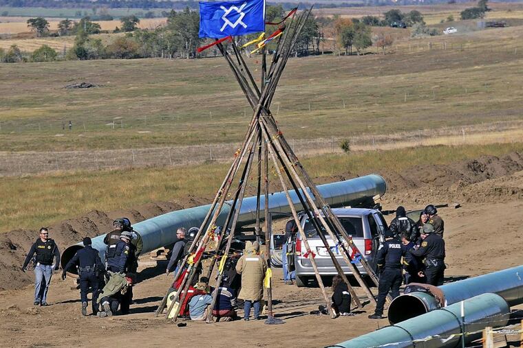 In this Oct. 10, 2016, law-enforcement officers (left) drag a person from a protest against the Dakota Access pipeline, near the town of St. Anthony in rural Morton County, N.D.