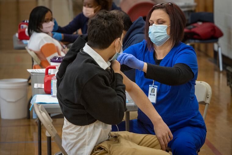 Registered nurse Sherry Holbrook administers a COVID-19 vaccine in the Northeast High School gymnasium in February.