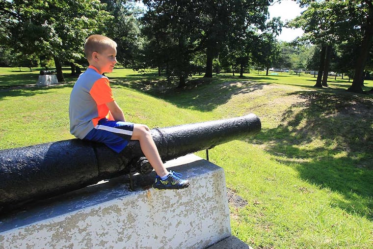 Luke Janofsky, 7, looks over the old trenches from the battlefield as he sits on a cannon. His mother, Jennifer Janofsky, is a Rowan history professor and Red Bank Battlefield curator.