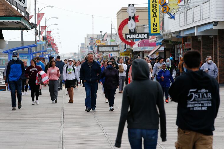 Walkers stroll across the Wildwood Boardwalk in Wildwood, N.J., on Sunday, May 24, 2020, the second day of a slow Memorial Day weekend.