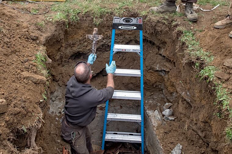 Mike Krolikowski of Bradbury Vault Co. holds up a crucifix found in the casket. All that was left of
the priest was his skull and a few bones.