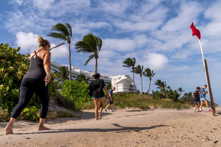 A red flag, signaling high surf and strong currents, flies in strong wind on the beach in Palm Beach, Fla., on Tuesday as Tropical Storm Nicole threatens. Its aftermath will have some impacts here after our run of palm tree weather.