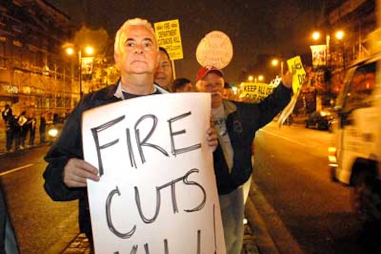 Retired firefighter Lou Lupo holds a protest sign on the South Broad Street median last week after Mayor Nutter announces the proposes closing of his local fire company, Engine 6. (Jonathan Wilson/Staff Photographer)