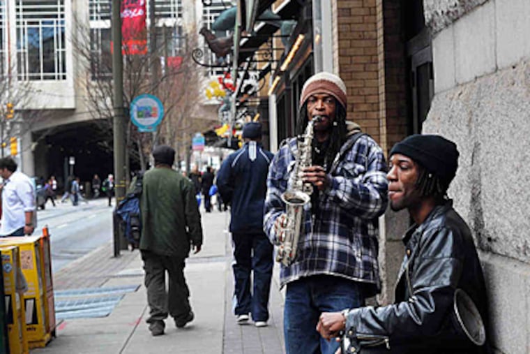 On 12th Street, by a Reading Terminal entrance, Jesse Andrus (left) and David Buckery, play their music for passersby and hopefully handouts. ( Sharon Gekoski-Kimmel / Staff Photographer )