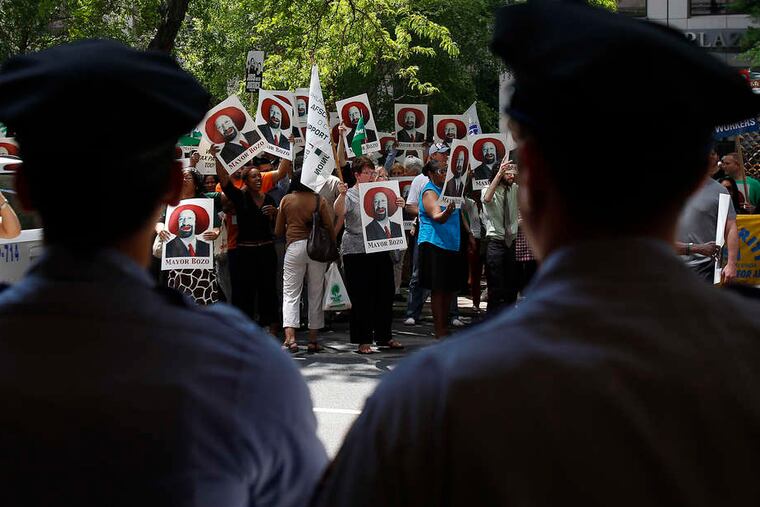 DAVID MAIALETTI / STAFF PHOTOGRAPHER Police officers watch as union members mock Mayor Nutter with homemade signs yesterday outside a gathering of the U.S. Conference of Mayors at the Westin in Center City. For more, see Page 11.