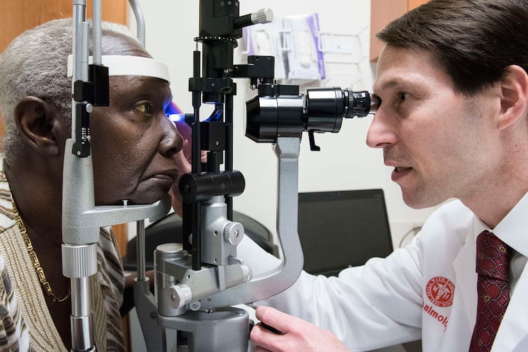 Jonathan Myers, of Wills Eye Hospital, examines Rose Carvalho in West Philadelphia. Medical practices are offering eye exams at primary-care offices or dental services during pediatric visits and taking blood pressure at barbershops.