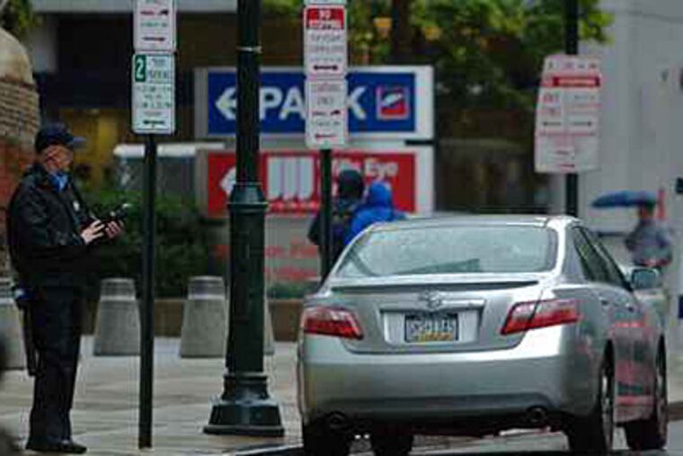 A Philadelphia Parking Authority officer writes a ticket in this file photo. (John Costello / Staff Photographer)