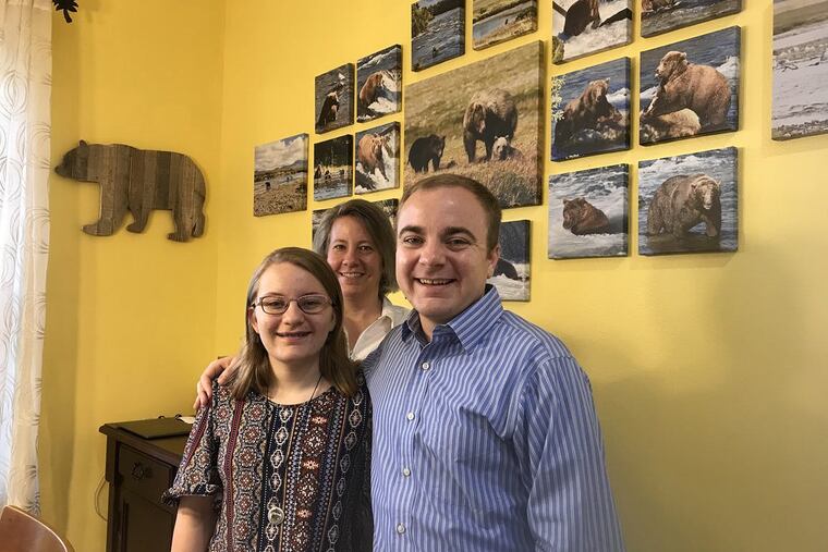 Megan Sorbo, left, with her mother, Tina, and brother, Trevor, at the family’s home near Orlando. The bear photographs on the wall were taken by Megan’s mom during a vacation to Katmai National Park and Preserve in Alaska.