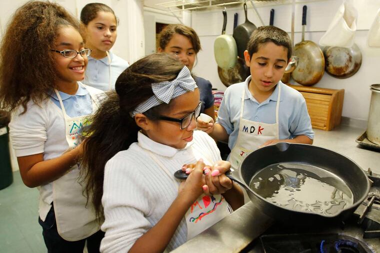 At Wiggins Prep School in Camden, Aa'myrah Bethea, 10, coats the heavy cast-iron skillet with olive oil for sautéing vegetables for a whole-wheat pasta dish the class was making.